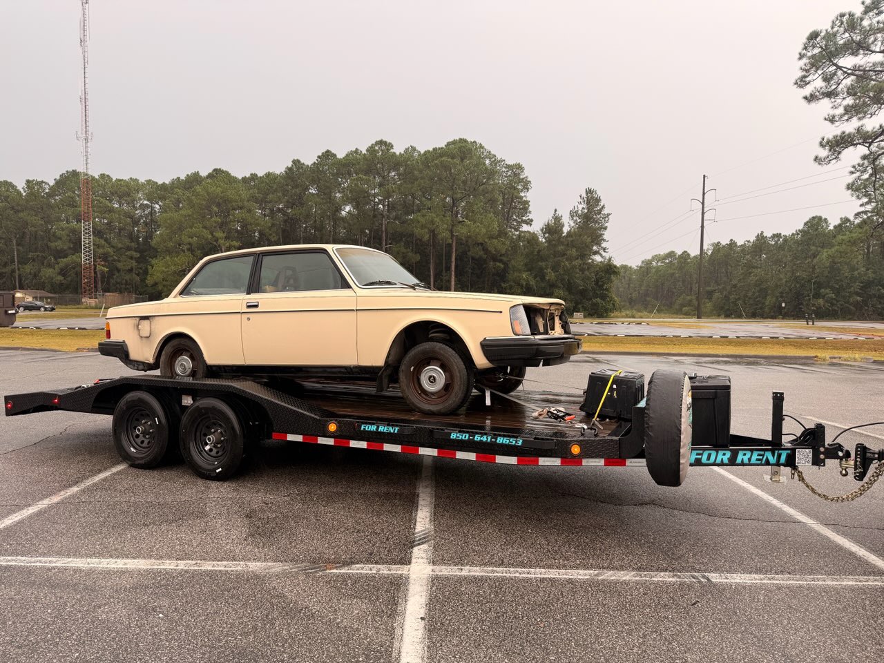 Vintage cream Volvo car on black trailer with FOR RENT signage