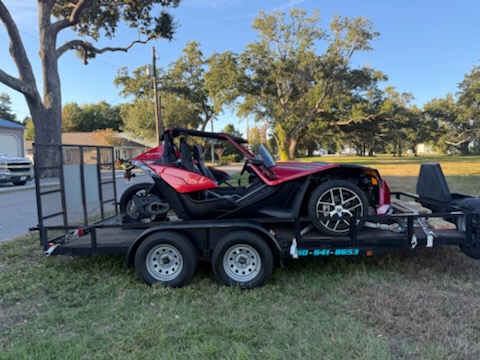 Red Polaris Slingshot on trailer from rear angle in park