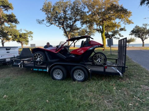 Red Polaris Slingshot secured on car hauler in park setting